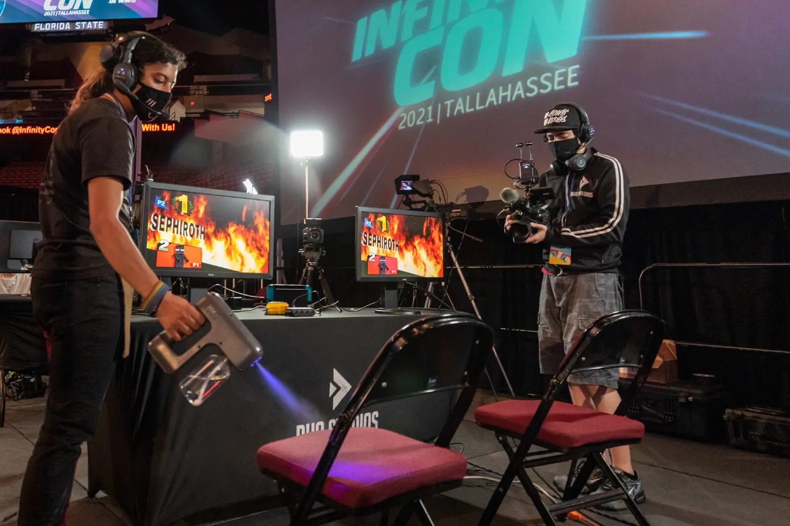 An InfinityCON Staff member sanitizes the stream setup between sets on stage during top 8
